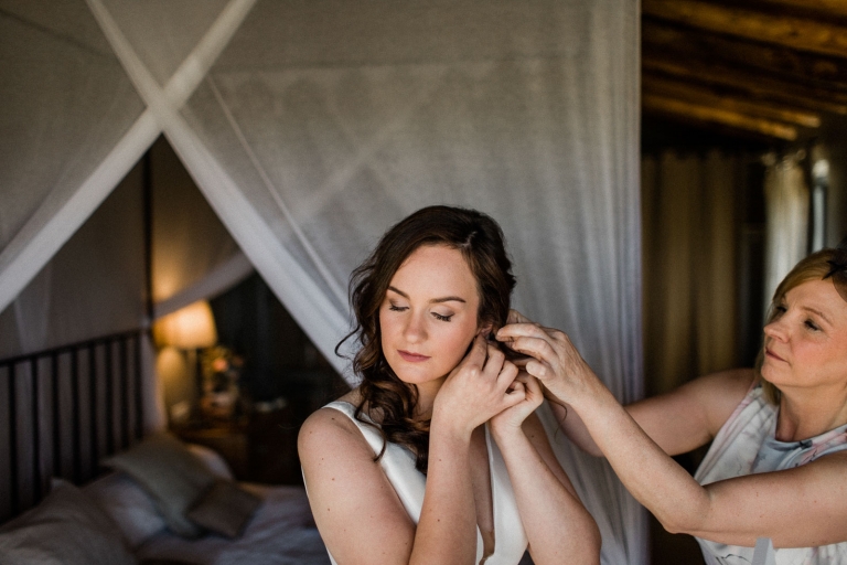 bride getting ready for wedding with help of her mother