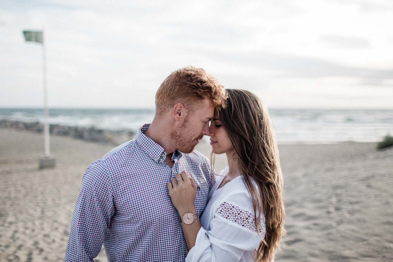 couple standing facing each other beside sea