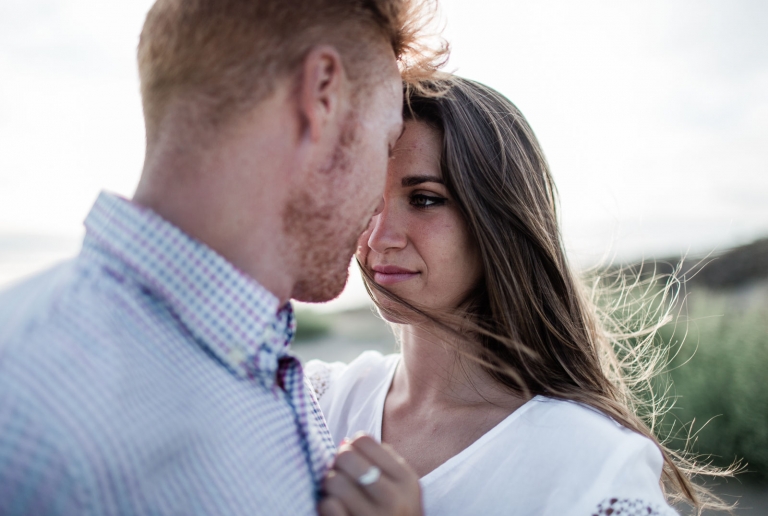 couple standing facing each other beside sea