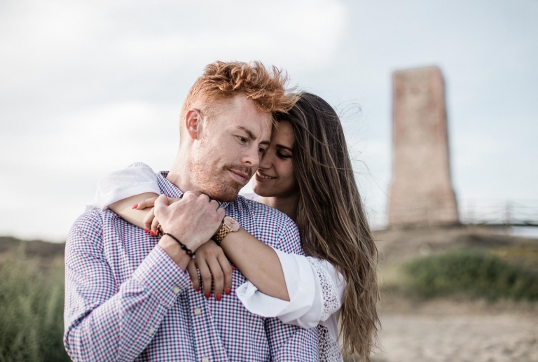 couple standing on beach sand 