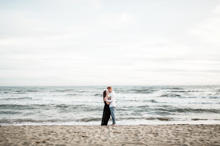photo of the couple standing on beach sand 