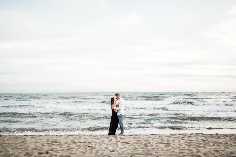 photo of the couple standing on beach sand 