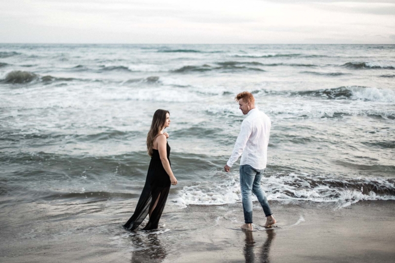 photo of the couple standing on beach sand facing each other