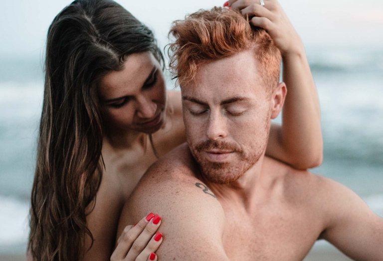 couple gently touch each other on the sand